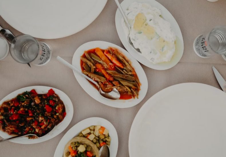 Top view of various delicious food on table with dishware and silverware in restaurant on daytime